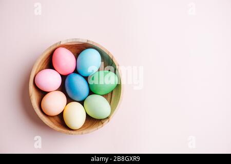 Painted multi-colored easter eggs in a wooden bowl. Top view. Stock Photo