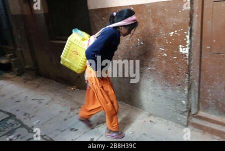 Kathmandu, Nepal. 22nd Mar, 2020. A small girl carries the filled water jar from a water supply shop in Kathmandu, Nepal, March 22, 2020. Credit: Sunil Sharma/Xinhua/Alamy Live News Stock Photo
