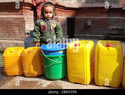 Kathmandu, Nepal. 22nd Mar, 2020. A kid stands in front of empty water jars near a traditional stone tap in Kathmandu, Nepal, March 22, 2020. Credit: Sunil Sharma/Xinhua/Alamy Live News Stock Photo