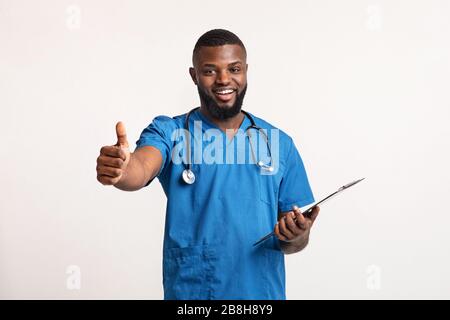 Positive black man doctor showing thumbs up at camera Stock Photo