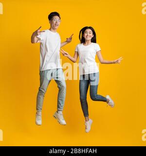 Happy young asian man and woman jumping up while posing Stock Photo