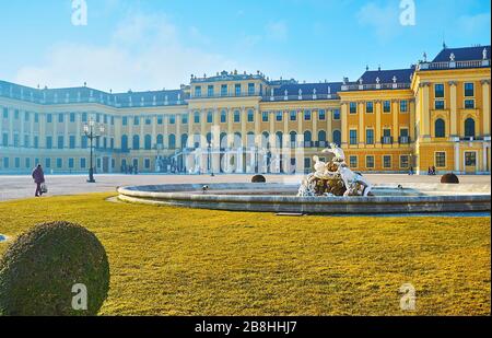 VIENNA, AUSTRIA - FEBRUARY 19, 2019: The green lawn and  Ehrenhof fountain (Ehrenhofbrunnen) in front of the Baroque building of Schonbrunn Palace, on Stock Photo