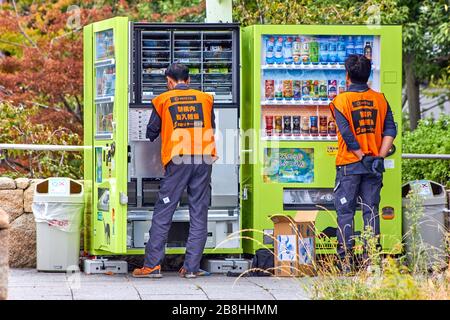 Worker in uniform changing drinks in vending machine in Japan Stock Photo