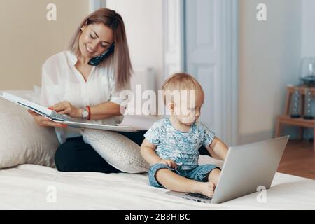 Business mom talking on a cell phone. Multi-tasking, freelance and motherhood concept Stock Photo
