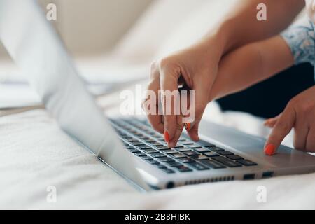 Young mother with her child working on laptop in bedroom at home. Multi-tasking, freelance and motherhood concept. Close up Stock Photo