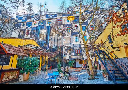 VIENNA, AUSTRIA - FEBRUARY 19, 2019: The courtyard of Kunst Haus Wien with tables of outdoor cafe and unusual wall of the Hundertwasser museum, on Feb Stock Photo