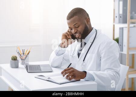 Young african doctor talking to patient on phone Stock Photo