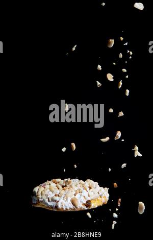 falling peanuts on cookies, cookies with peanuts on black background. Stock Photo