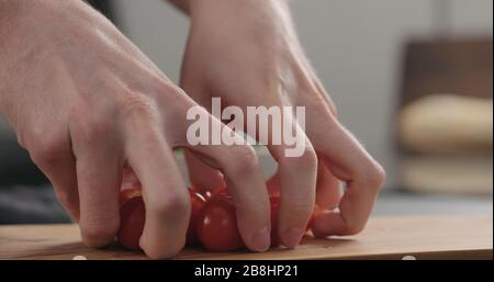 closeup man hands take cherry tomatoes from olive board, wide photo Stock Photo