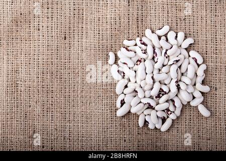 Raw black-eyed beans are scattered on the background of burlap. Place for text. Stock Photo