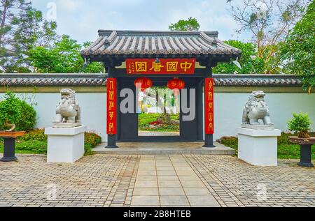 CHIANG MAI, THAILAND - MAY 7, 2019: The entrance to the garden of China with black gate, tile roof, red lanterns and stone statues of Pixiu lion-drago Stock Photo