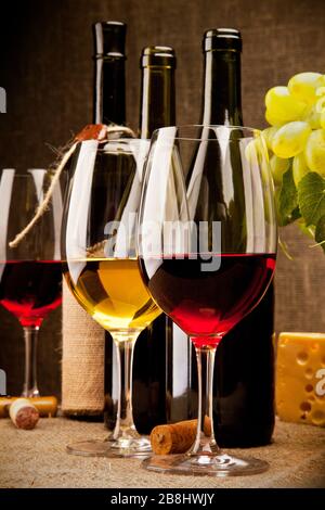 Still life with wine bottles, glasses, grapes and cheese Stock Photo