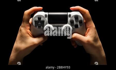 Hyman hands holding white video game gamepad isolated on a black ...