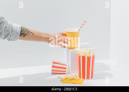 Soda cup with straw and popcorn in recyclable paper striped bucket held by woman Stock Photo