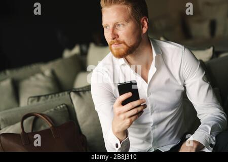 Happy young man using his smart phone at office Stock Photo
