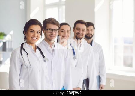 Group of practicing doctors with stethoscope are smiling while standing in the clinic office. Stock Photo