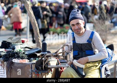 Shoemaker working with stitching machine at the Street Market, Khiva, Uzbekistan Stock Photo
