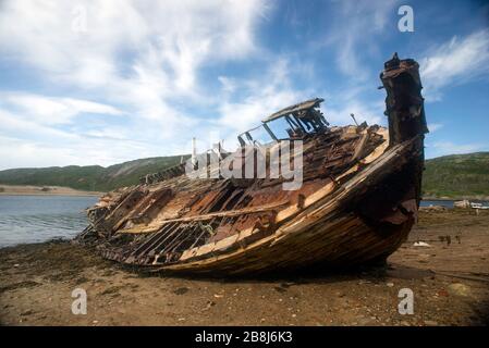 Old abandoned fishing boat, slowly rotting on the shore, Teriberka, Kola Penninsula, Russia Stock Photo