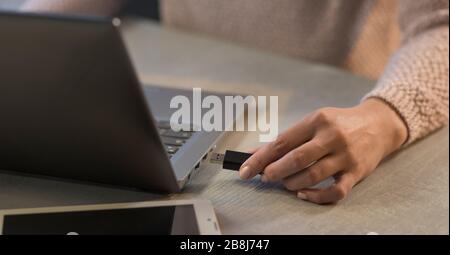 Woman plugging a USB drive into her laptop, technology and data storage concept Stock Photo
