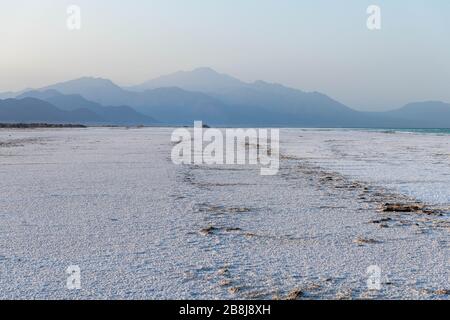 Africa, Djibouti, Lake Assal. Salt texture on the ground with mountains in the background Stock Photo