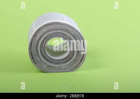 toilet paper made out of newspapers, alternative toilet paper, isolated on green, close-up, newspaper roll Stock Photo