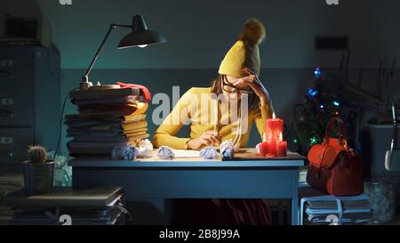 Efficient secretary working late at night in the office on Christmas Eve, she is doing difficult calculations Stock Photo