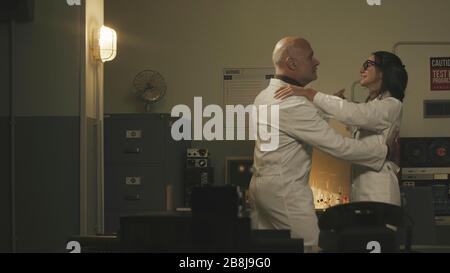 Couple of scientists dancing together in a vintage style lab and smiling Stock Photo