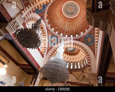 BEIRUT, LEBANON - 01 Apr 2017: The decorated mosque cupola from inside, with Arabic script paintings and hanging glass chandeliers in Al-Amine mosque, Stock Photo