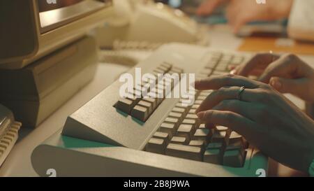 Scientist typing on a keyboard and using computer in a vintage lab, hands close up Stock Photo