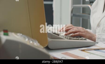 Woman working with an old vintage computer in a laboratory, data analysis and IT technology concept Stock Photo