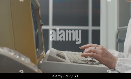 Woman working with an old vintage computer in a laboratory, data analysis and IT technology concept Stock Photo