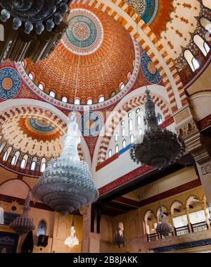 BEIRUT, LEBANON - 01 Apr 2017: The decorated mosque cupola from inside, with Arabic script paintings and hanging glass chandeliers in Al-Amine mosque, Stock Photo