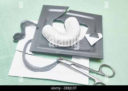 Process of creating custom mouthguard. Silver sports mouthguard with pieces of plastic material and tools on a work table. Stock Photo