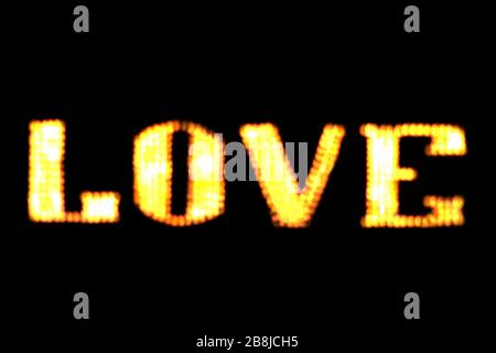 blurred text LOVE sign LED Bokeh light yellow gold on dark wall, Neon Light led letter Love on background black Stock Photo
