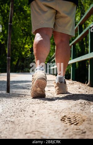 Woman legs with trekking boots leaving a footprint on the road Stock Photo