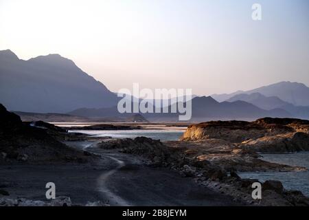 Africa, Djibouti, Lake Assal. Landscape view of lake Assal with mountains in the background. and a a road in the left foreground. Stock Photo