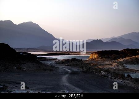 Africa, Djibouti, Lake Assal. Landscape view of lake Assal with mountains in the background. and a a road in the left foreground. Stock Photo