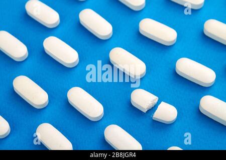 Row of White pills on blue background. Stock Photo