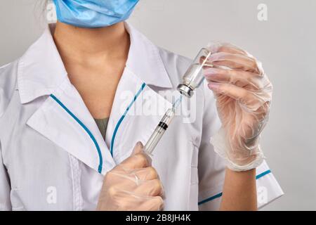 Fimale doctor injecting syringe into a vial bottle with medicine.
