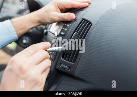 Car interior cleaning and detailing. Hand holding and using soft brush. Stock Photo