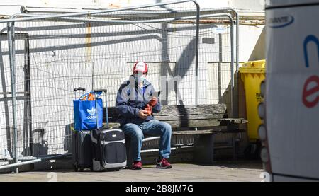 Brighton UK 22nd March 2020 - Travellers in protective masks wait for a coach at the Pool Valley bus station in Brighton today during the Coronavirus COVID-19 pandemic crisis  . Credit: Simon Dack / Alamy Live News Stock Photo