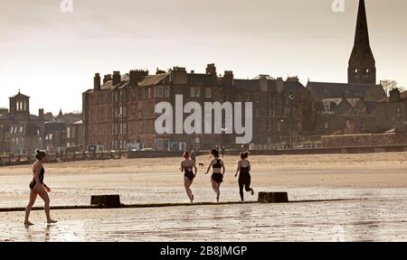 Portobello, Edinburgh, Scotland, UK. 22nd Mar, 2020. Early hazy sunshine with an early morning temperature of 2 degrees centigrade rising to 8 degrees with sunny blue skies by noon.Wild swimmers out early but appeared to be staggering their dips to avoid the normally larger groups to assist social distancing. Stock Photo