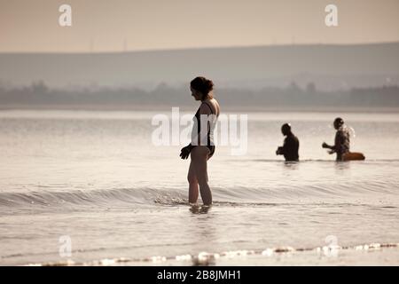 Portobello, Edinburgh, Scotland, UK. 22nd Mar, 2020. Early hazy sunshine with an early morning temperature of 2 degrees centigrade rising to 8 degrees with sunny blue skies by noon.Wild swimmers out early but appeared to be staggering their dips to avoid the normally larger groups to assist social distancing. Stock Photo