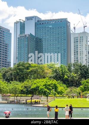 Office and residential high rise towers and fountains in Symphony Lake and tourists enjoying a day at KLCC Park Kuala Lumpur Malaysia. Stock Photo