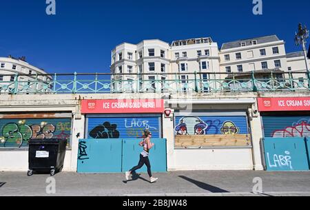 Brighton UK 22nd March 2020 - A runner on Brighton seafront this morning in some Brighton but cold Spring sunshine  during the Coronavirus COVID-19 pandemic crisis . Credit: Simon Dack / Alamy Live News Stock Photo