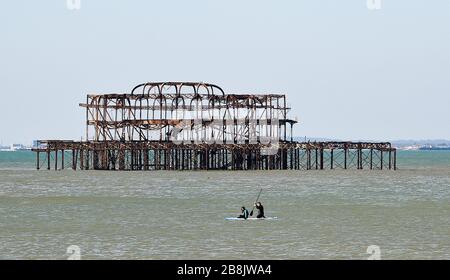 Brighton UK 22nd March 2020 - Paddle boarders  enjoy some Spring sunshine today in Brighton during the Coronavirus COVID-19 pandemic crisis . Credit: Simon Dack / Alamy Live News Stock Photo