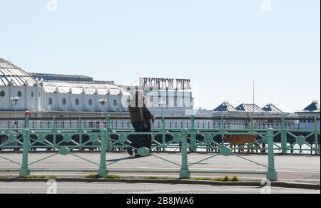 Brighton UK 22nd March 2020 - Visitors enjoy some Spring sunshine today along Brighton seafront which looks quiet this lunchtime during the Coronavirus COVID-19 pandemic crisis . Credit: Simon Dack / Alamy Live News Stock Photo