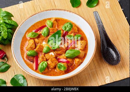 Thai Panang Chicken Curry in white plate at black slate background. Phanaeng Curry is thai cuisine dish with chicken, kaffir lime leaves, red curry sa Stock Photo