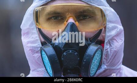 The young europeans man in protective chemical suit and respirator, outdoors. New coronavirus (COVID-19). Concept of health care during an epidemic or Stock Photo