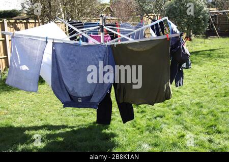 Rotary clothes airer drying washing in a UK garden in Spring 2020 Stock Photo